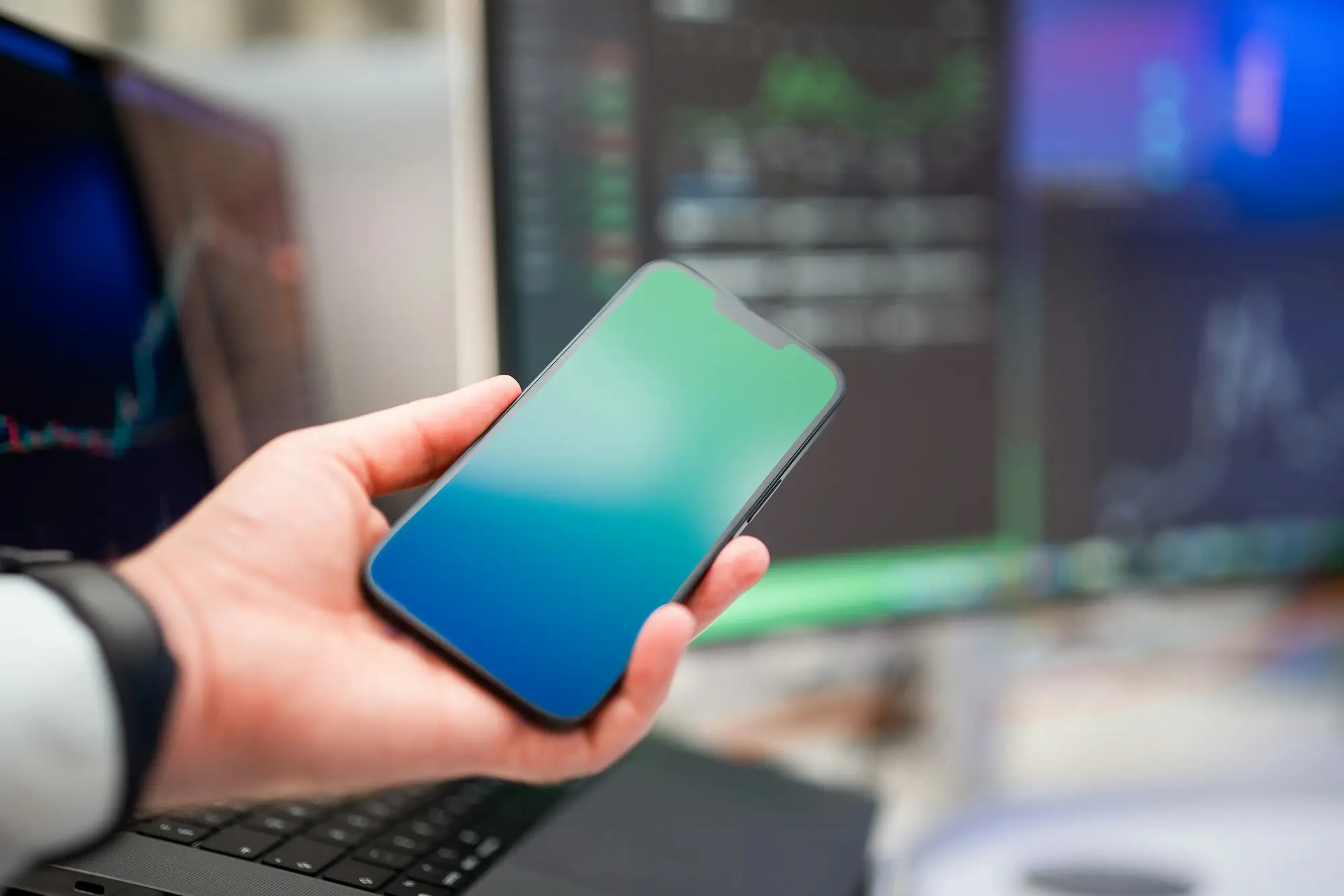 Business owner at a desk holding a smartphone, about to check a text message offering a pre-approved business loan